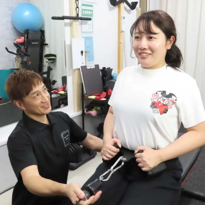 トレーナーが女性に寄り添ってトレーニング指導している様子。リバウンド防止のための継続サポートをイメージ